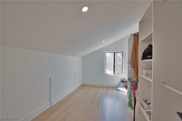 additional living space with vaulted ceiling and light hardwood / wood-style floors