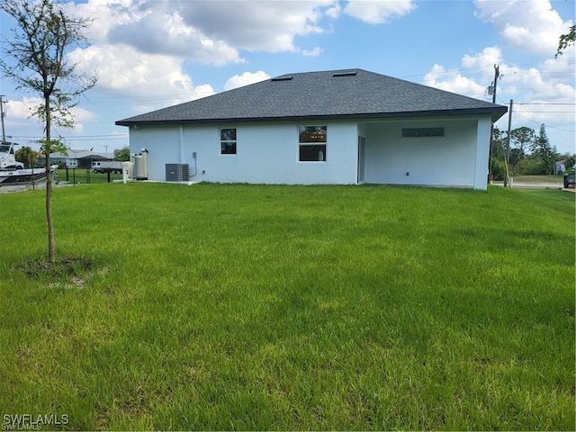 rear view of property featuring central AC unit and a lawn