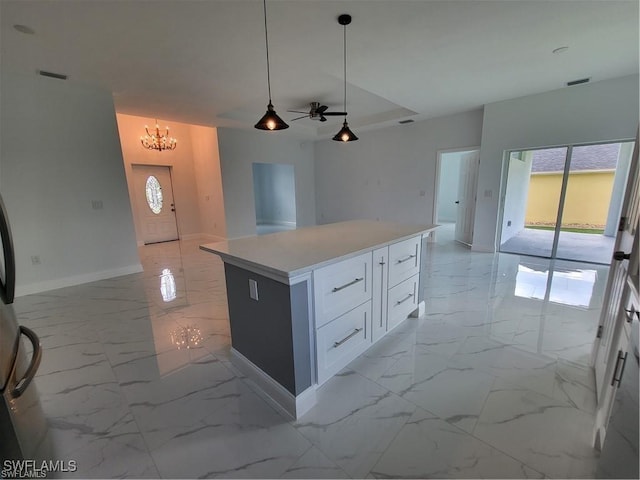 kitchen featuring decorative light fixtures, a center island, ceiling fan with notable chandelier, and white cabinets