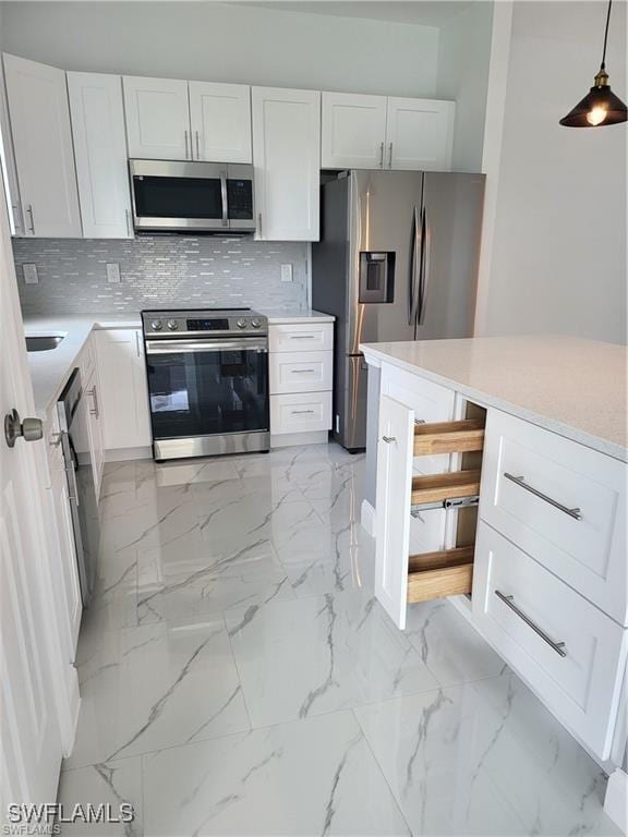 kitchen with white cabinetry, appliances with stainless steel finishes, pendant lighting, and backsplash