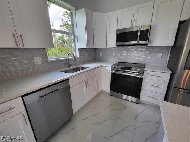 kitchen with sink, appliances with stainless steel finishes, tasteful backsplash, light stone countertops, and white cabinets