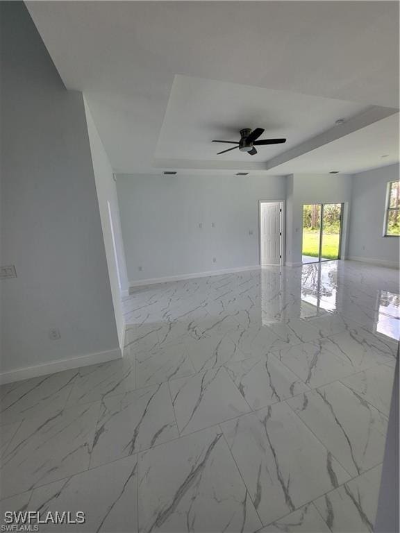 unfurnished room featuring ceiling fan and a raised ceiling