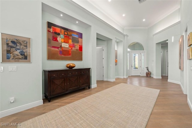 corridor with ornamental molding and light hardwood / wood-style flooring