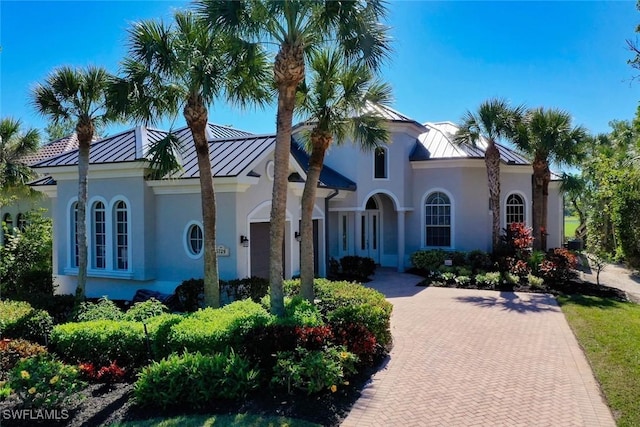 mediterranean / spanish-style house with stucco siding, decorative driveway, metal roof, and a standing seam roof