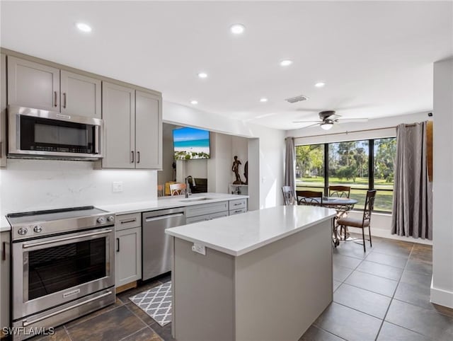 kitchen with stainless steel appliances, gray cabinets, sink, and a kitchen island