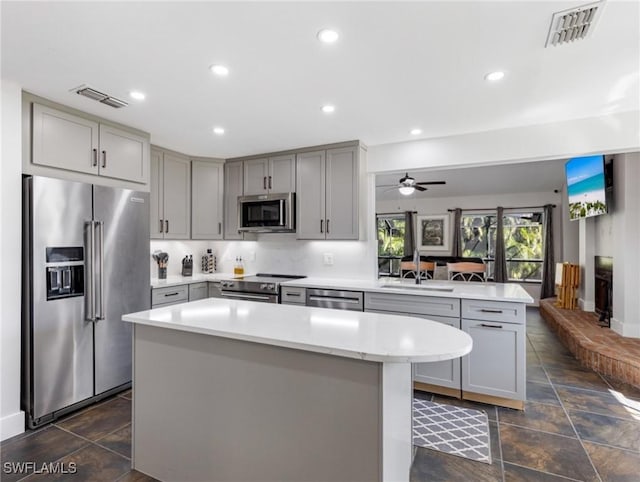 kitchen featuring sink, stainless steel appliances, kitchen peninsula, and a kitchen island