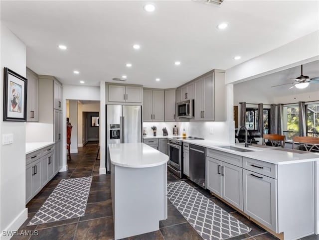 kitchen with sink, gray cabinetry, stainless steel appliances, a center island, and kitchen peninsula