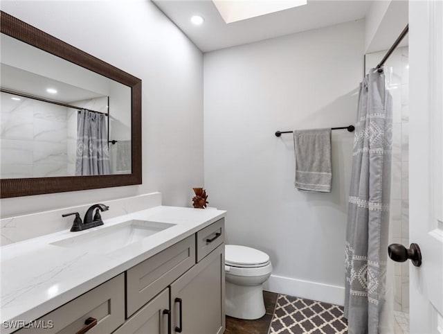 bathroom featuring vanity, curtained shower, a skylight, and toilet