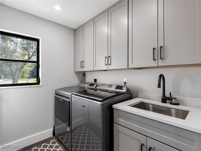 washroom with sink, cabinets, independent washer and dryer, and dark tile patterned flooring