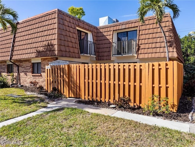 view of side of home with a balcony and a yard