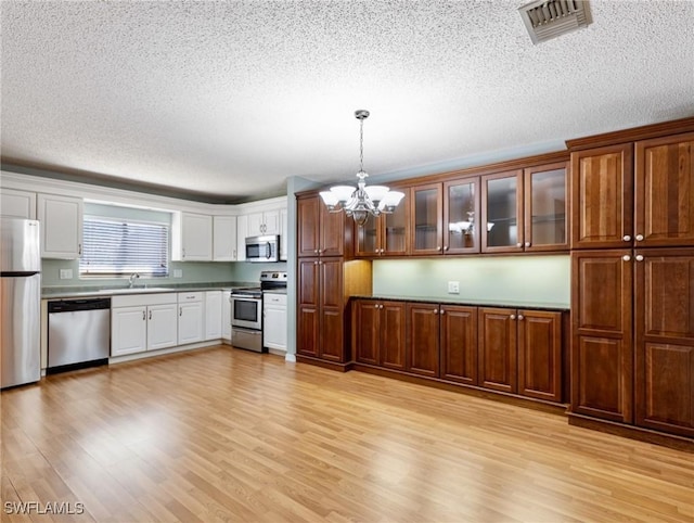 kitchen featuring pendant lighting, sink, light wood-type flooring, and appliances with stainless steel finishes