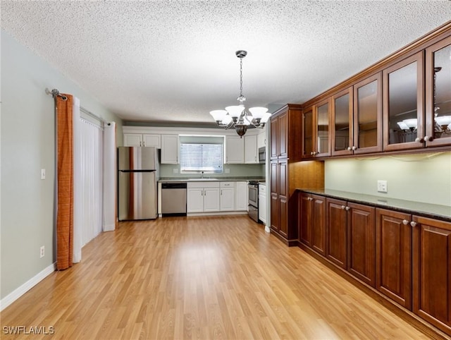 kitchen featuring pendant lighting, sink, appliances with stainless steel finishes, a chandelier, and light wood-type flooring