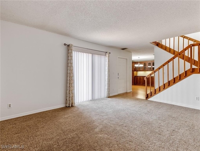 unfurnished living room featuring carpet flooring, a chandelier, and a textured ceiling