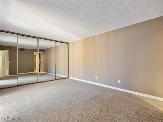 empty room with carpet flooring and a textured ceiling