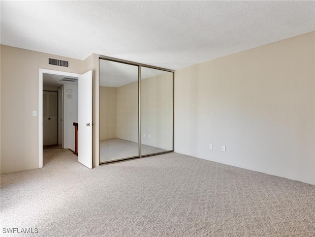 unfurnished bedroom with carpet floors, a closet, and a textured ceiling