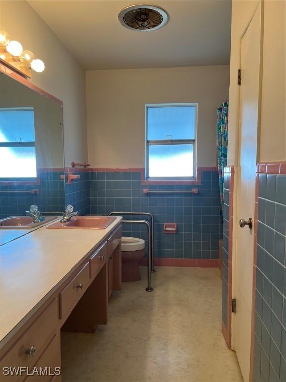 bathroom featuring vanity, toilet, a shower with shower curtain, and tile walls