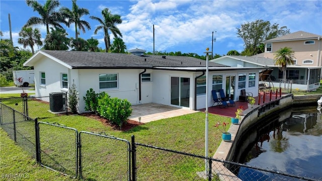 back of house featuring cooling unit, a sunroom, a patio area, and a lawn