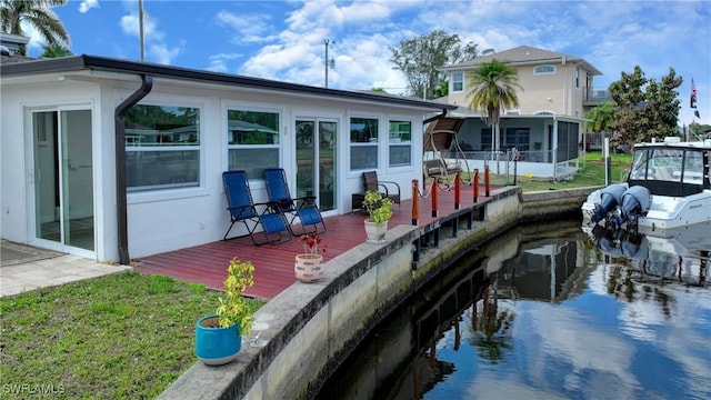 back of house with a wooden deck, a sunroom, and a lawn