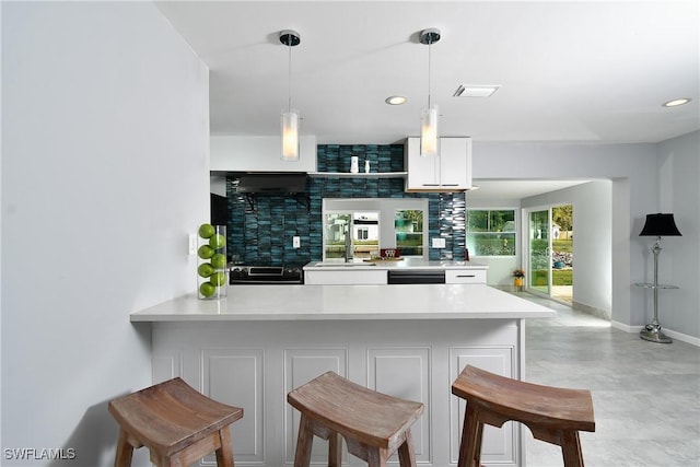 kitchen with sink, dishwasher, white cabinets, decorative light fixtures, and kitchen peninsula