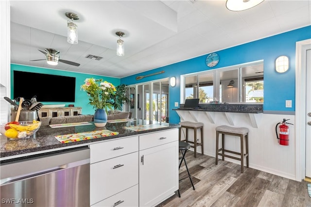 kitchen with white cabinetry, wood-type flooring, dark stone countertops, dishwasher, and ceiling fan