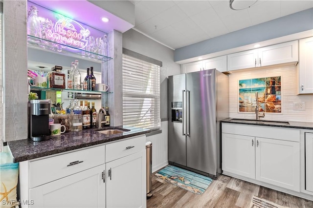 kitchen with dark stone countertops, sink, high end refrigerator, and white cabinets