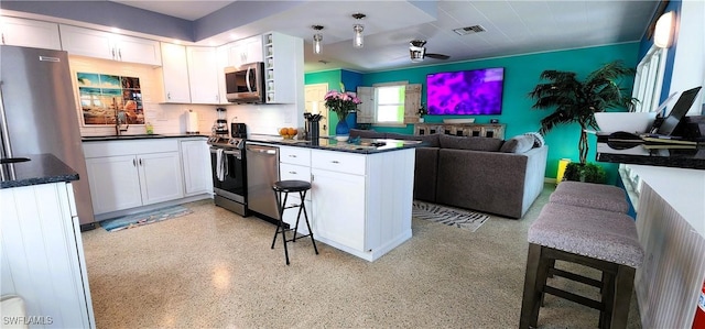 kitchen featuring stainless steel appliances, sink, white cabinets, and a kitchen bar