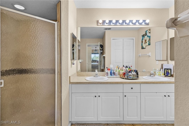 bathroom featuring a shower with shower door and vanity