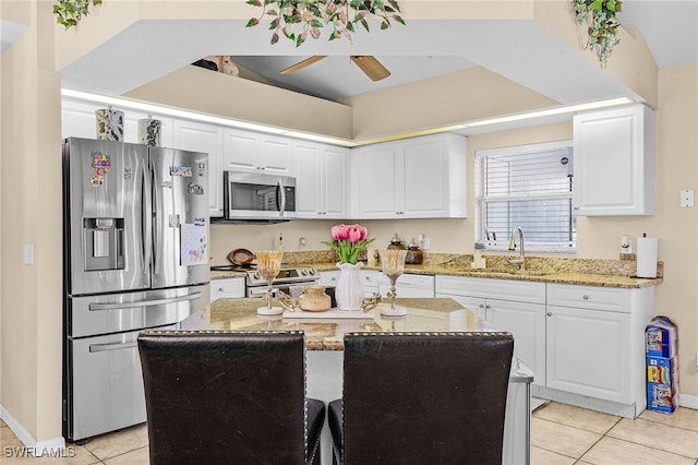 kitchen featuring appliances with stainless steel finishes, sink, a center island, white cabinets, and light stone countertops