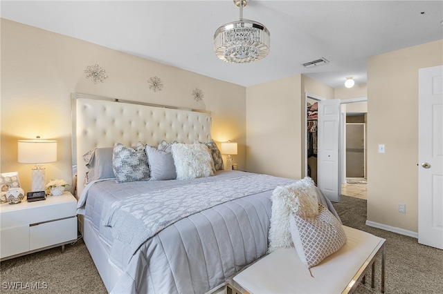 carpeted bedroom featuring a chandelier, a walk in closet, and a closet