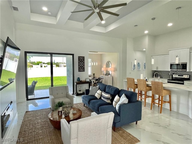 living room with beamed ceiling, sink, a high ceiling, coffered ceiling, and ceiling fan