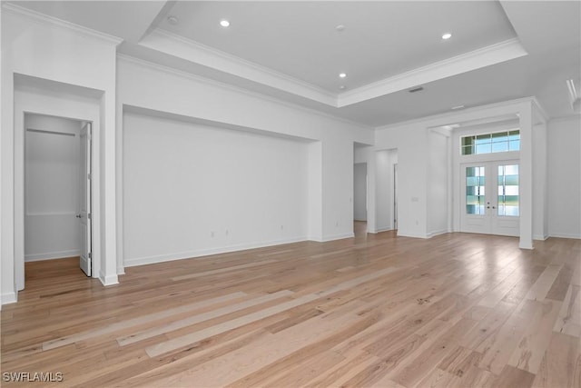 unfurnished living room with french doors, ornamental molding, light wood-type flooring, and a tray ceiling