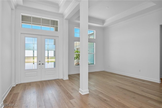 entryway with crown molding, a raised ceiling, light hardwood / wood-style flooring, and french doors