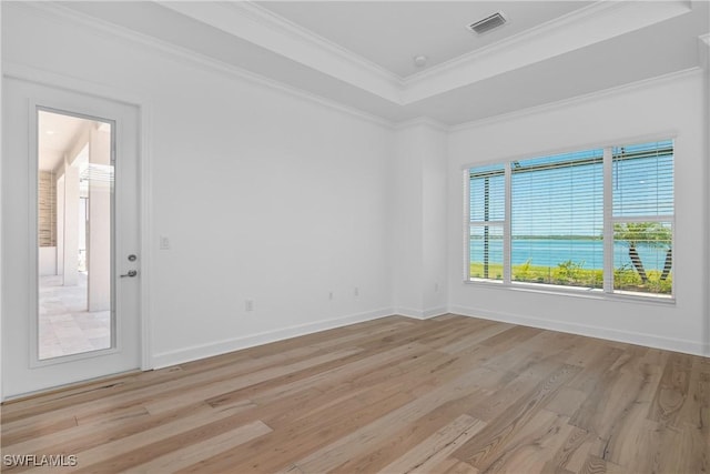 unfurnished room featuring a raised ceiling, crown molding, and light hardwood / wood-style floors