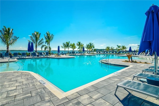 view of swimming pool featuring a patio and a water view