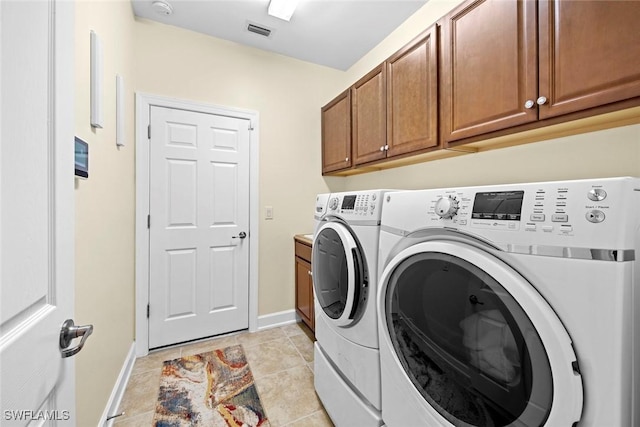 laundry area featuring cabinets, washer and dryer, and light tile patterned floors