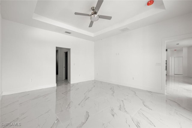 spare room with ceiling fan and a tray ceiling