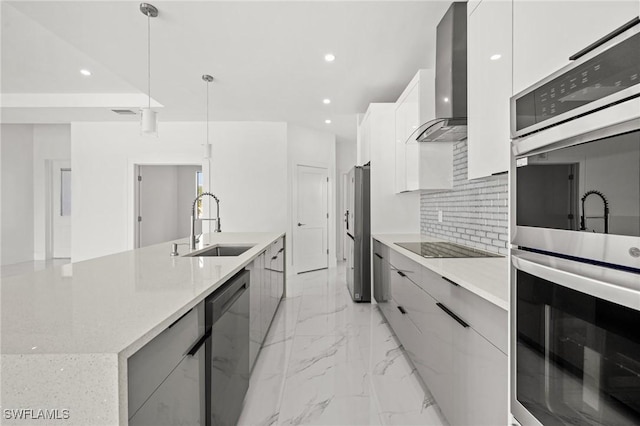 kitchen with sink, wall chimney range hood, hanging light fixtures, black appliances, and white cabinets