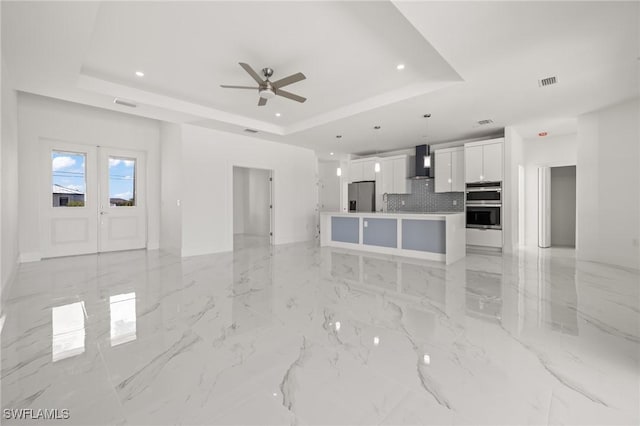 living room with a raised ceiling and ceiling fan