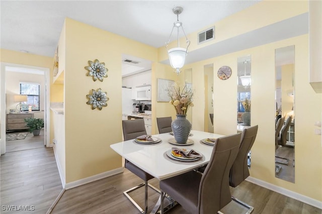 dining area with visible vents, baseboards, and wood finished floors