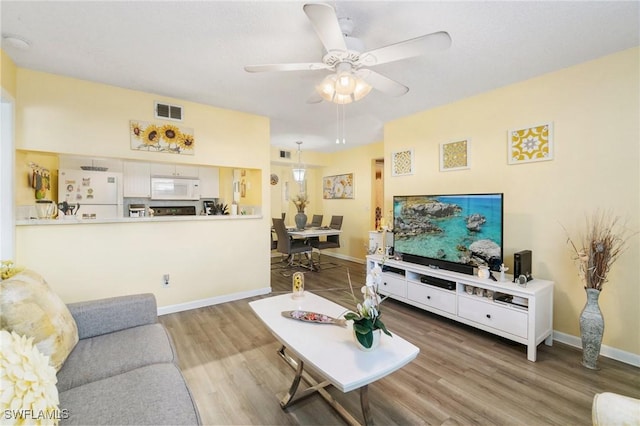 living room featuring visible vents, baseboards, a ceiling fan, and wood finished floors