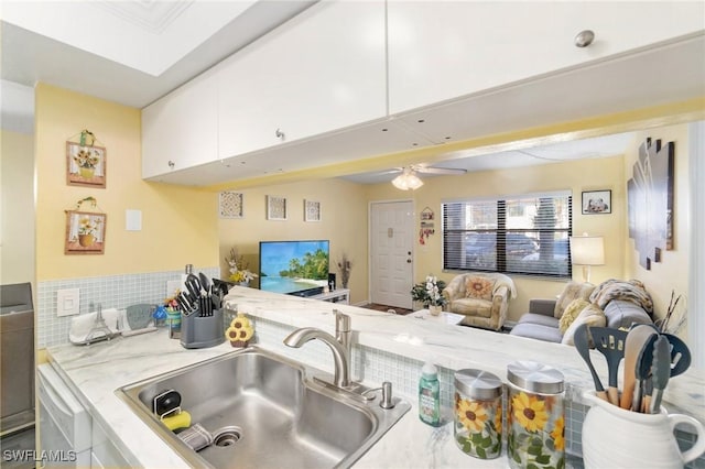 kitchen featuring ceiling fan, light stone countertops, open floor plan, white cabinetry, and a sink