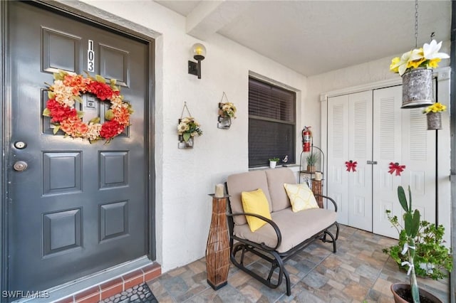 doorway to property featuring stucco siding and covered porch