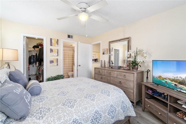 bedroom with visible vents, ensuite bathroom, wood finished floors, a closet, and a spacious closet