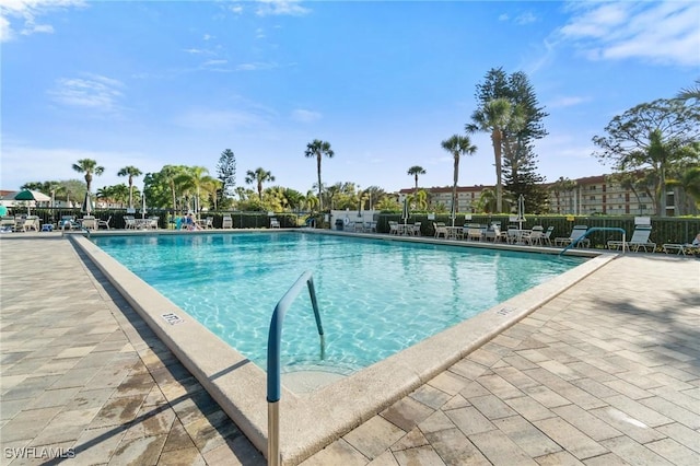 community pool with a patio area and fence