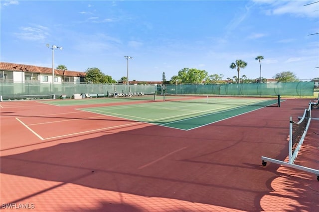 view of tennis court with community basketball court and fence