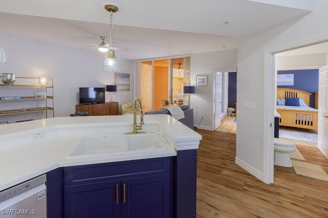 kitchen featuring sink, light hardwood / wood-style flooring, blue cabinetry, ceiling fan, and white dishwasher