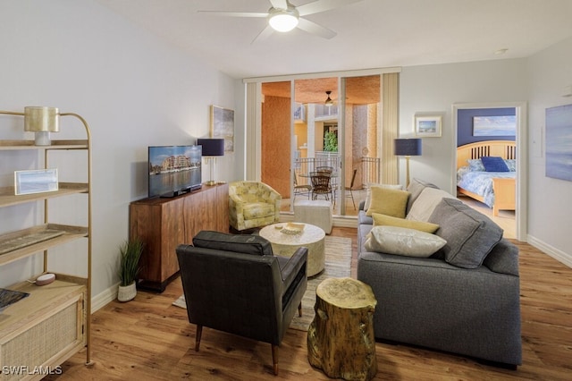 living room with wood-type flooring, ceiling fan, and a wall of windows