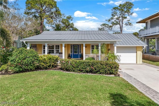 ranch-style house with metal roof, driveway, stucco siding, a front lawn, and a standing seam roof