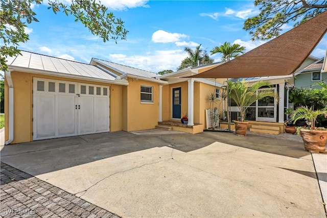 view of front of home featuring driveway, entry steps, a standing seam roof, and stucco siding