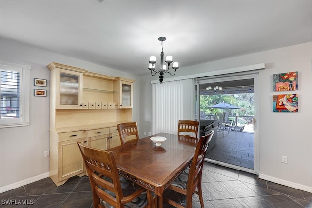 dining area with an inviting chandelier, dark tile patterned floors, and baseboards